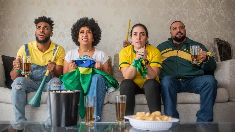Pessoas sentadas assistindo jogo do Brasil.